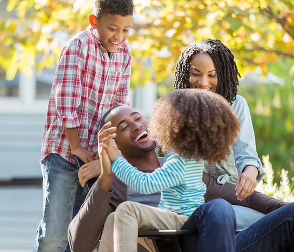 A father laughing with his son and daughter while the mother looks on, smiling together outdoors